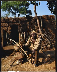 Burkina Faso, province de Poni, pays des Lobi, Loropéni, paysan et chasseur dans sa cour posant avec les attributs des initiés: l'arc, le carquois et la houe