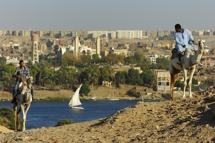 Egypt, Upper Egypt, Nubia, Nile Valley, Aswan, the city and camel driver on the sand dunes of the left bank
