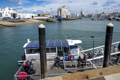 France, Vendée (85), Les-Sables-d'Olonne, cyclistes utilisant le bac traversant le port, fresque retracant l'histoire de la ville peinte sur les silos de la coopérative Cavac par l'artiste basque Taroe en arrière plan