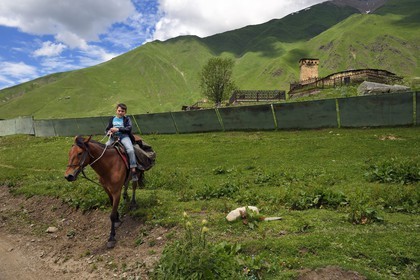 Georgia, Upper Svaneti (Zemo Svaneti), village of Ushguli, listed as World heritage by UNESCO, young rider in front of Lamaria St. Mary's church of Ushguli from the 12th century