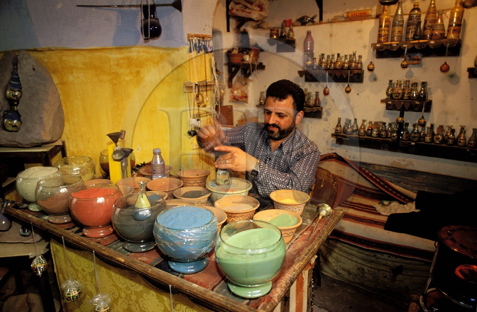 Jordanie, Madaba, artisan créant les bouteilles aux dessins de sables colorés vendues comme souvenirs aux touristes
