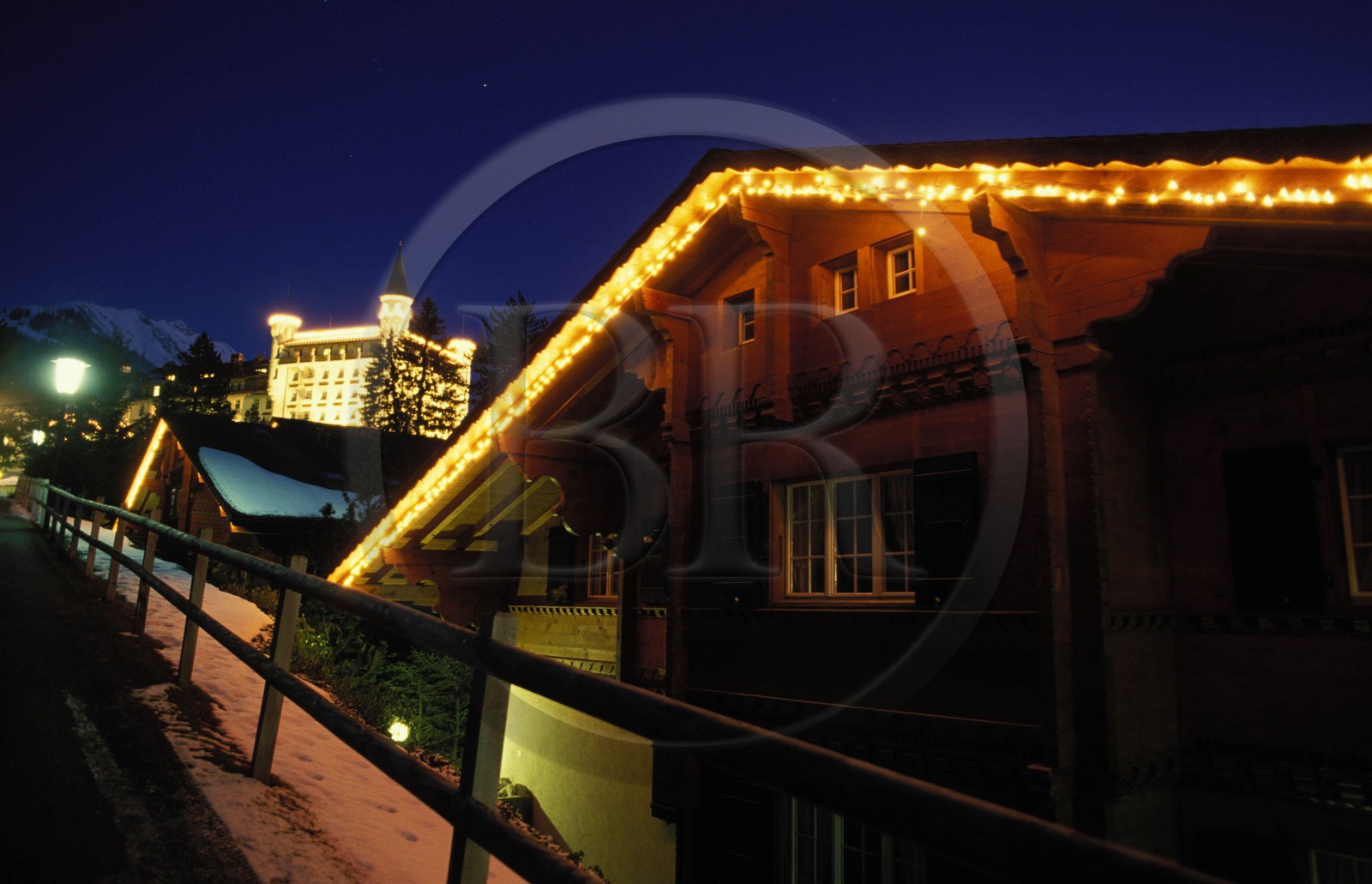 Switzerland, region of Bern (Bernese Oberland), Saanenland, Gstaad, the Palace Hotel by night behind a wooden chalet