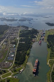 Panama, Colon province, Panama Canal, Panamax cargo passing the Gatun locks, the construction of the new locks on the left and the Gatun Lake in the background (aerial view)
