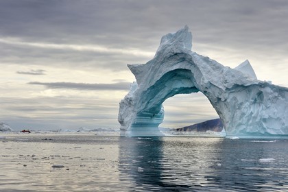 Groenland, cote Nord-Ouest, mer de Baffin, Inglefield Fjord vers Qaanaaq, iceberg formant un arche et un PolarCirkel boat (zodiac) d'exploration du bateau de croisière MS Fram de la compagnie Hurtigruten