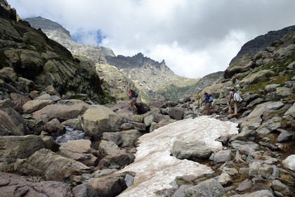France, Alpes-Maritimes, parc national du Mercantour (Mercantour National Park), the Vallee des Merveilles (Valley of Wonders) scattered with thousands of rupestral engravings of the Bronze Age, hikers on the trail GR 52 towards the Baisse (pass) de Valmasque and the Mont Grand Capelet (2915 m) in the background