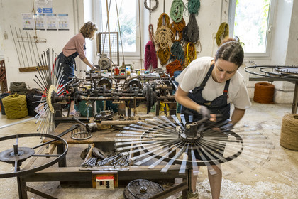 France, Drome, Drome provencale, Nyons, La Scourtinerie, the last scourtin factory in Provence, traditional filters used in the production of olive oil but also designed today as decorative objects made of coconut fiber, manufacturing of scourtins in their workshop on custom-made machines, Sophie Villeneuve-Fert adjusts one of the circular weaving machines at the needle assembly station