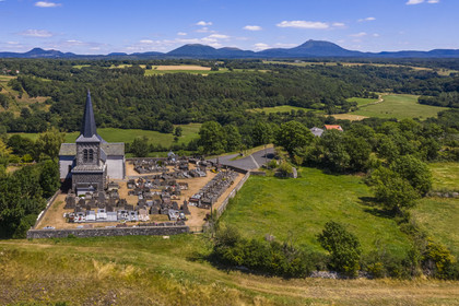 France, Puy de Dome, church on the basalt mound of Saint Pierre Le Chastel overlooking the Sioule valley, the Chaine des Puys listed as World heritage by UNESCO, with the Puy de Côme on the left, the Grand Suchet and the Puy de Dôme volcano on the right (aerial view)