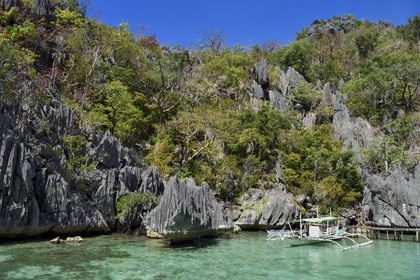Philippines, Calamian Islands dans le nord de Palawan, Coron Island Natural Biotic Area, pirogue à balancier au pied des rochers de calcaire