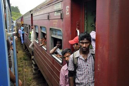 Sri Lanka, Central Province, the popular scenic train ride through the tea growing hill country between Hatton and Badulla, Great Western train station, passengers hanging on the door