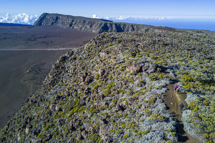 France, Ile de la Reunion, Parc National de la Réunion classé Patrimoine Mondial de l'UNESCO, sur les pentes du volcan de Piton de la Fournaise, randonneurs sur le sentier de l'oratoire Ste Thérèse au dessus de la Plaine des Sables que l'on aperçoit en contrebas (vue aérienne)