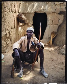 Burkina Faso, Poni province, Lobi land, Loropéni region, head of family posing with bow and arrows in front of the entrance of his house in the village of Lakar