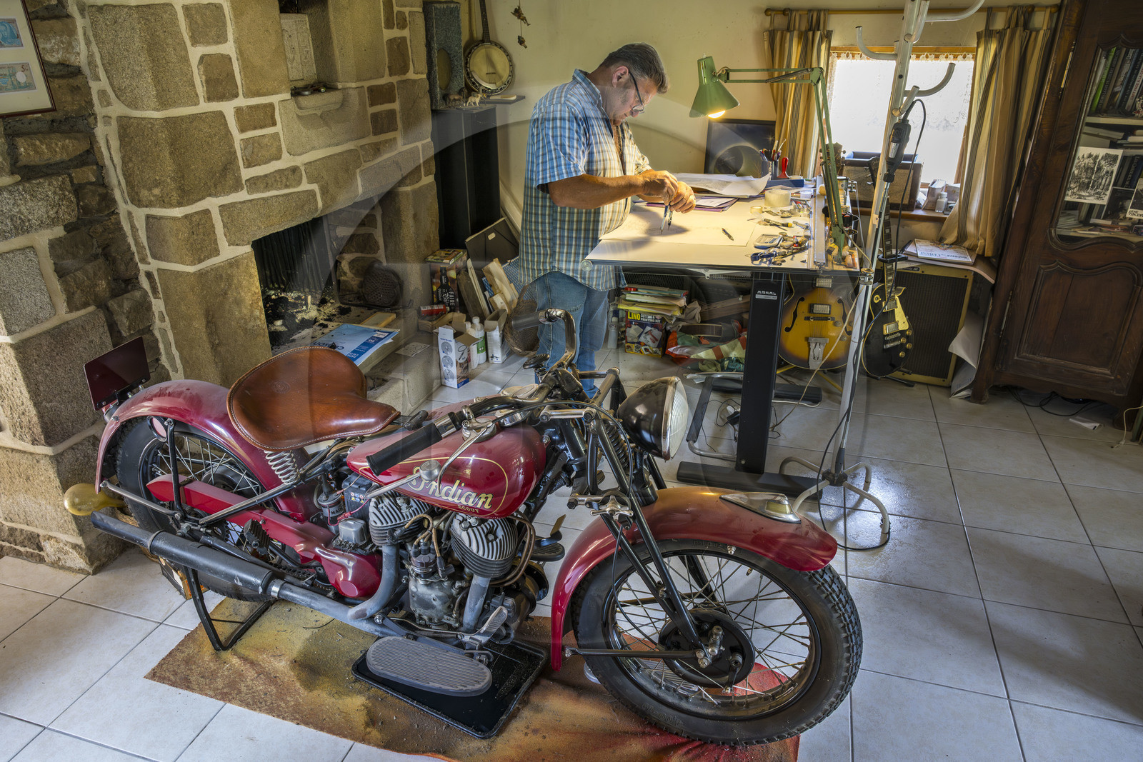 France, Morbihan (56), Locoal-Mendon, le sculpteur et tailleur de pierre Gueho Patrick dans son bureau avec une moto Indian scout de 1940 France, Morbihan (56), Locoal-Mendon, le sculpteur et tailleur de pierre Gueho Patrick dans son bureau avec une moto Indian scout de 1940