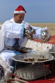 Morocco, Oriental Region, man in ceremonial cloth serving mint tea on the beach