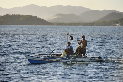 Philippines, Calamian Islands in northern Palawan, Coron bay, outrigger canoe and Busuanga Island in the background