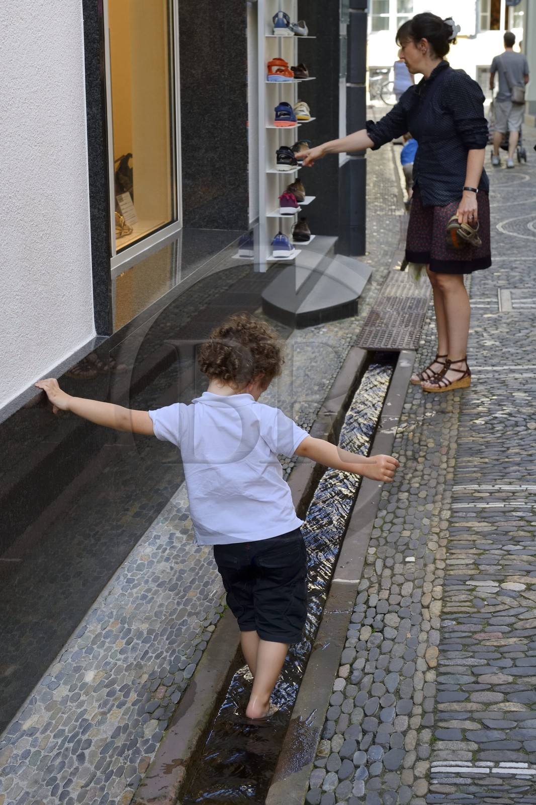 Allemagne, Bade-Wurtemberg, Fribourg en Brisgau, enfant jouant dans un des Bächle qui sont des petits caniveaux ouverts qui bordent les trottoirs