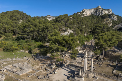 France, Bouches-du-Rhône (13), Parc Naturel Régional des Alpilles, Saint-Rémy-de-Provence, site archéologique de Glanum au pied du massif des Alpilles, colonnes et entablement reconstitués du petit temple géminé du premier forum au premier plan à droite (vue aérienne)