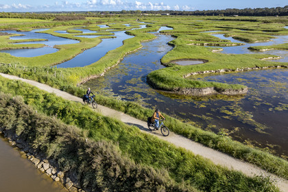 France, Vendée (85), Talmont-Saint-Hilaire, marais de la Guittière dans l'arrière pays de la Pointe du Payré, cycliste sur la piste de la véloroute Vendée Vélo Tour et Vélodyssée au passage du Cul d’Ane, marais aménagés pour la pisciculture de dorades, mulets et anguilles (vue aérienne)
