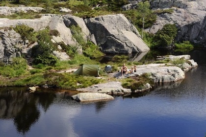 Norway, Rogaland County, around Lysefjord, campers on the edges of a small lake on the hiking trail leading to Preikestolen Rock