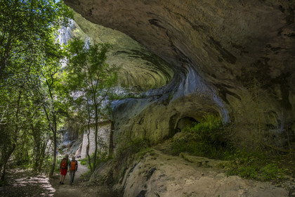 France, Vaucluse (84), Parc naturel régional du Mont Ventoux, Monieux, Gorges de La Nesque, randonneurs marchand sous une barre rocheuse au fond du canyon vers la chapelle Saint-Michel du XIIe siècle