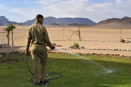 Namibia, Hardap region, Namib Desert East of the Namib Naukluft National Park towards Sossusvlei, the Mirage Resort & Spa, an employee sprinkles the lawn at the edge of the desert