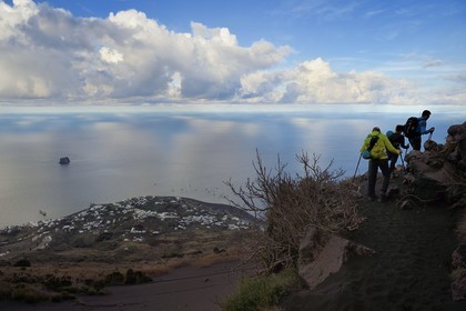 Italie, Sicile, iles Eoliennes, classées Patrimoine Mondial de l'UNESCO, ile de Stromboli, randonneurs dans l'ascension du volcan, le village de Stromboli et l'ilot de Strombolicchio en arrière plan