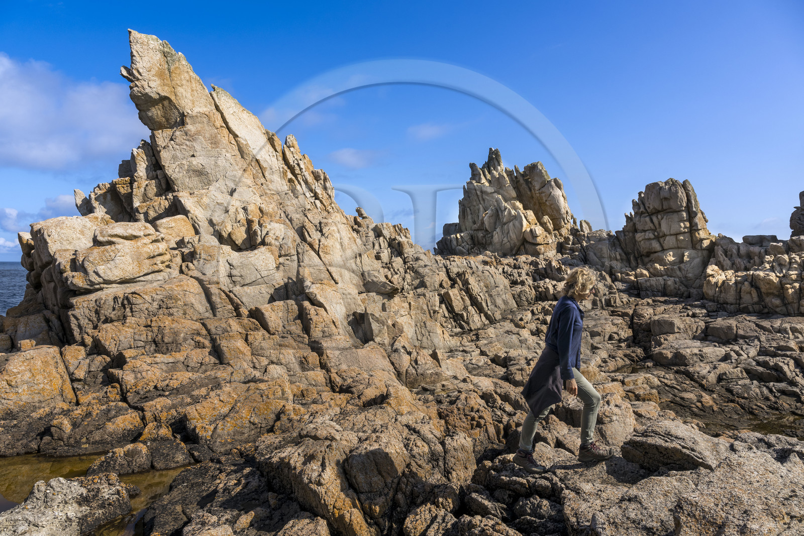 France, Finistère (29), Mer d'Iroise, Ile d'Ouessant, randonneuse dans les rochers façonnés par les tempêtes au pied du phare du Créac’h