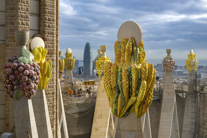 Espagne, Catalogne, Barcelone, quartier de l'Eixample, basilique de la Sagrada Familia de l'architecte du modernisme catalan Antoni Gaudi classée Patrimoine Mondial de l'UNESCO, sommets surmontés de mosaïques en forme de fruits entourant le chantier sur le toit de la nef à l'arrière de la future facade de la Gloire, la Torre Agbar de l'architecte Jean Nouvel en arrière plan