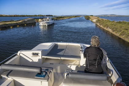 France, Hérault (34), Palavas-Les-Flots, navigation d'un bateau de plaisance Le Boat sur le canal du Rhône à Sète en bordure de l'étang du Méjean à droite