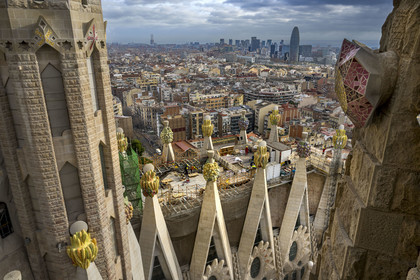 Espagne, Catalogne, Barcelone, quartier de l'Eixample, basilique de la Sagrada Familia de l'architecte du modernisme catalan Antoni Gaudi classée Patrimoine Mondial de l'UNESCO, sommets surmontés de mosaïques en forme de fruits entourant le chantier sur le toit de la nef à l'arrière de la future facade de la Gloire, la Torre Agbar de l'architecte Jean Nouvel en arrière plan