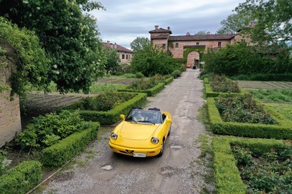 Italy, Emilia Romagna, Polesine Zibello near Parma, Antica Corte Pallavicina Hotel and restaurant, Alfa Romeo Duetto Spider yellow cabriolet (aerial view)