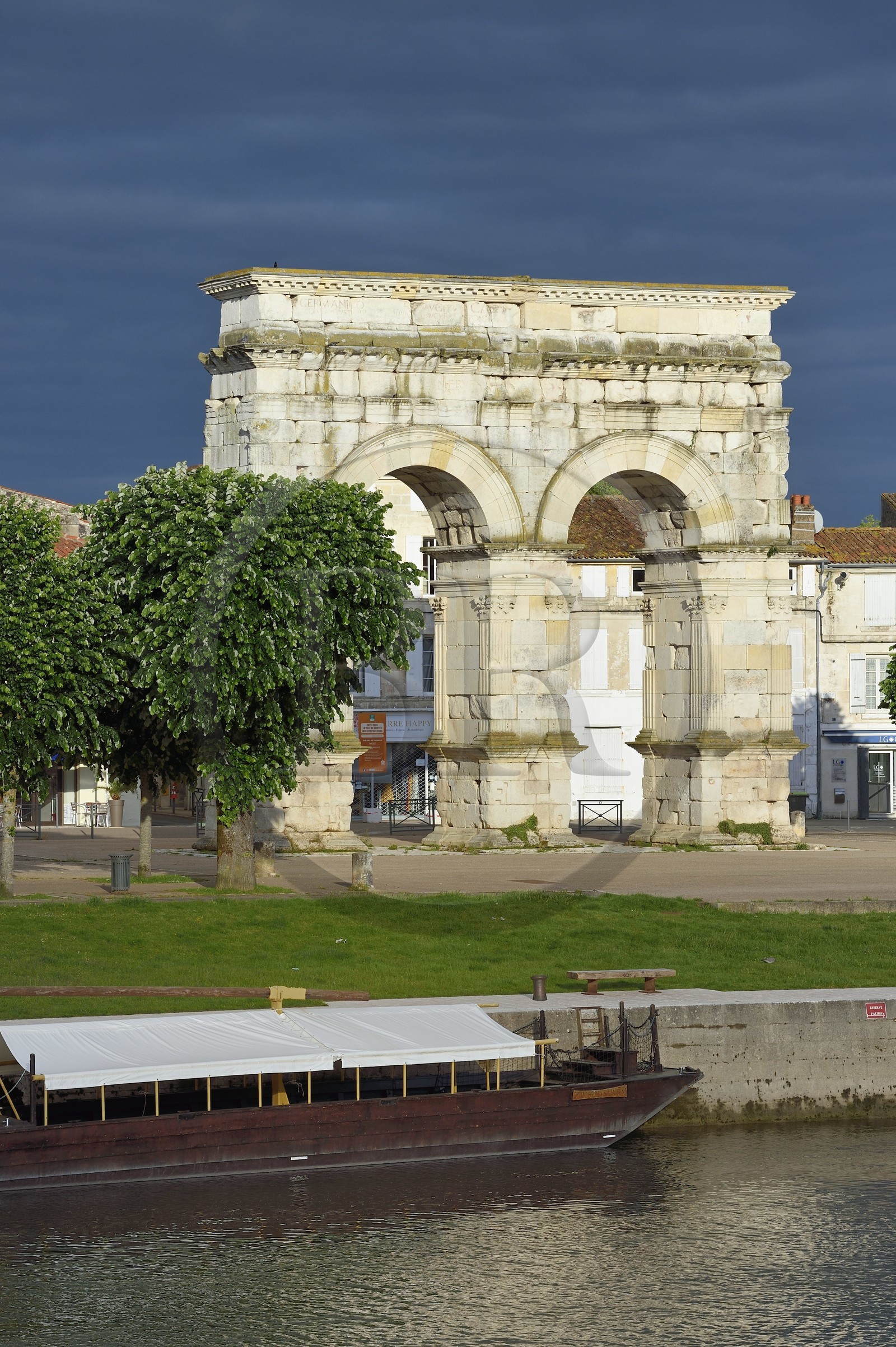 France, Charente-Maritime (17),  Saintonge, Saintes, l'arc de Germanicus est un arc routier en bordure de la Charente érigé en l'an 18-19 en l'honneur de l'empereur Tibère, son fils Drusus et son neveu et fils adoptif Germanicus, une gabarre au premier plan