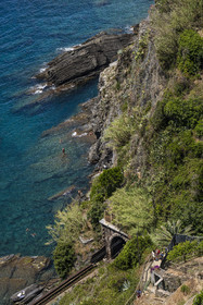 Italie, Ligurie, Cinque Terre, parc national des Cinque Terre classé Patrimoine Mondial de l'UNESCO, village de Vernazza, randonneurs sur le sentier du littoral GR 592 surplombant la voie de chemin de fer et les baigneurs au pied des falaises