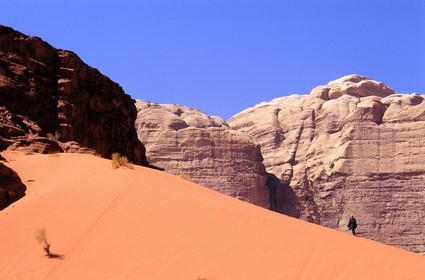 Jordan, Wadi Rum, tourist discovering the sensations of the desert on a dune of red sand