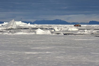 Groenland, cote Nord-Ouest, Smith sound au nord de la baie de Baffin, morceaux de glace de la banquise arctique et un PolarCirkel boat (zodiac) d'exploration du bateau de croisière MS Fram de la compagnie Hurtigruten, iceberg géant en arrière plan vers la côte canadienne de l'ile d'Ellesmere