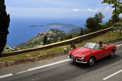 France, Alpes-Maritimes, collection convertible Alfa Romeo Giulietta on a road overlooking the hilltop village of Eze