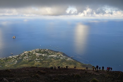 Italie, Sicile, iles Eoliennes, classées Patrimoine Mondial de l'UNESCO, ile de Stromboli, randonneurs dans l'ascension du volcan, le village de Stromboli et l'ilot de Strombolicchio en arrière plan