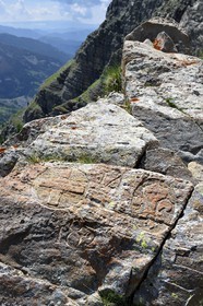 France, Alpes de Haute Provence, Uvernet Fours, Mercantour National Park, Ubaye valley, lake tour hiking trail of the Cayolle pass at the Pas du Lausson, boundary engraved on rocks delimiting the border between the Duchy of Savoy and the County of Nice, Haut-Var Valley and Lake Lausson (Alpes-Maritimes) in the background