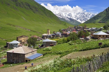 Georgia, Upper Svaneti (Zemo Svaneti), village of Ushguli, listed as World heritage by UNESCO, Svan defensive towers erected next to the houses and Mount Chkhara (highest peak in Georgia with 5,193 m) in the background, two farmers plow their field