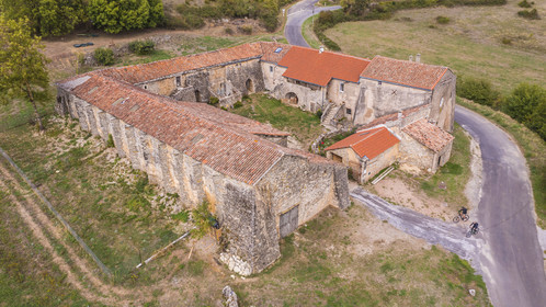 France, Aveyron, Grands-Causses Regional Nature Park, cyclists on the Brebis Cyclette tourist cycle route in the Pays de Roquefort, Mascourbe Farm which belonged to the Commandery of the Hospitallers of St. John of Jerusalem (aerial view)