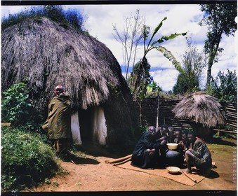 Burundi, Bujumbura Province, Ijenda area, main house of an intermediate type rugo, the archaic (pre colonial) rugo virtually disappeared, this hemispherical hut is differentiated only by having solid walls, the internal organization has not changed and it retains its thatched roof that covers it entirely, the two men left and right in the foreground are probably Hutu while the other men and women were Tutsi, the two ethnic groups live together without problems in peacetime and have good neighborly relations, the men are drinking the sorghum beer (traditional beer) (4x5 reversal film reproduction)