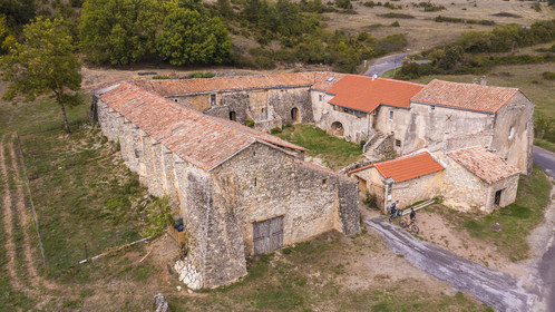France, Aveyron, Grands-Causses Regional Nature Park, cyclists on the Brebis Cyclette tourist cycle route in the Pays de Roquefort, Mascourbe Farm which belonged to the Commandery of the Hospitallers of St. John of Jerusalem (aerial view)