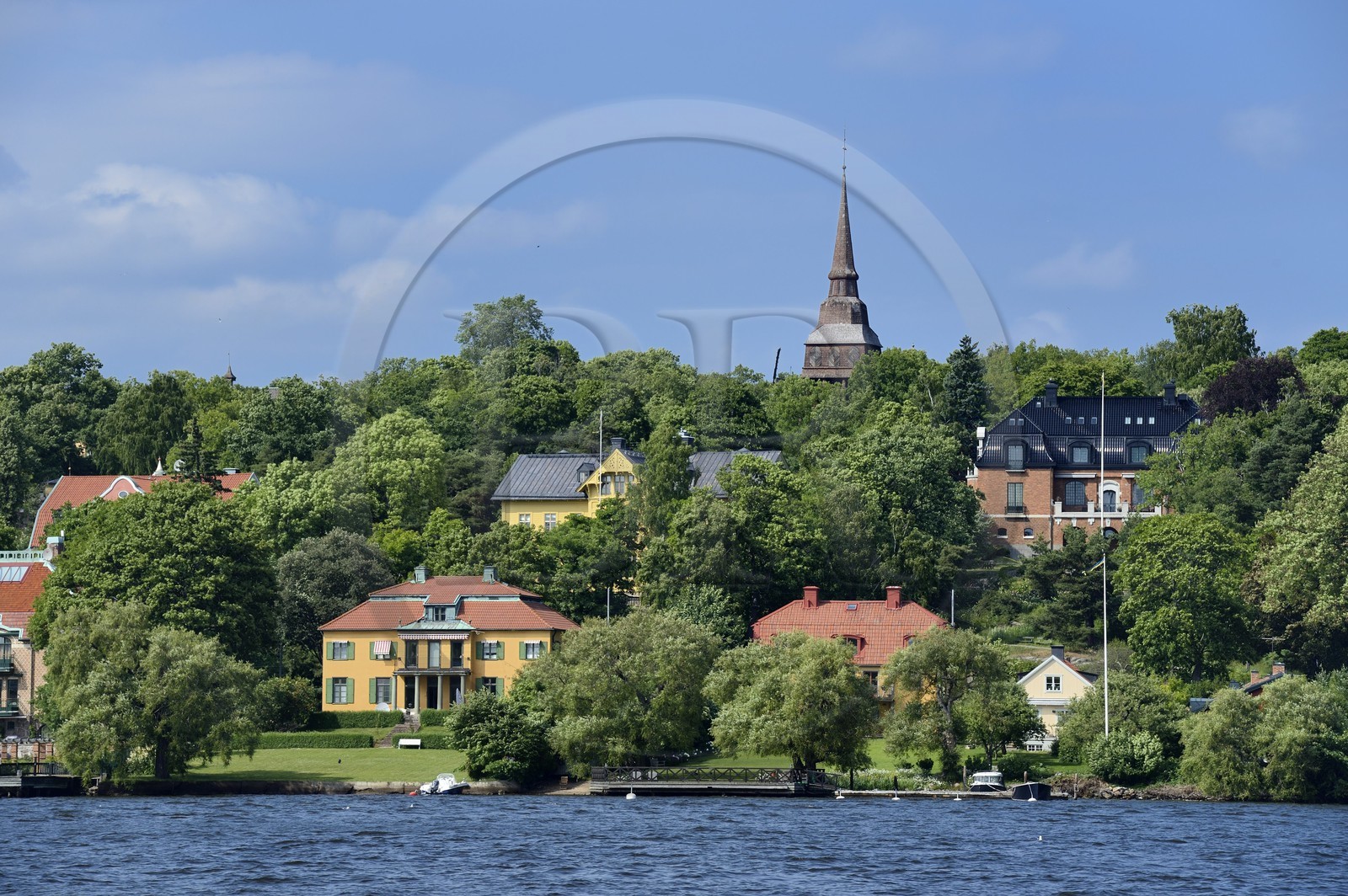 Suède, Stockholm, Djurgarden, villas du bord de mer et le beffroi Hallestad dans le musée de plein air Skansen en arrière plan