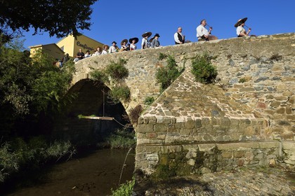 France, Var, Massif des Maures, Collobrières, group of traditional Provencal dancers and musicians at the chestnut festivals passing the bridge of the 12th century over the Real Collobrier river