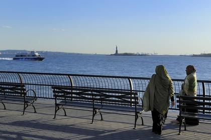 United States, New York City, Manhattan, South Point, Battery Park, veiled women walking along Battery Park and the Statue of Liberty in the background