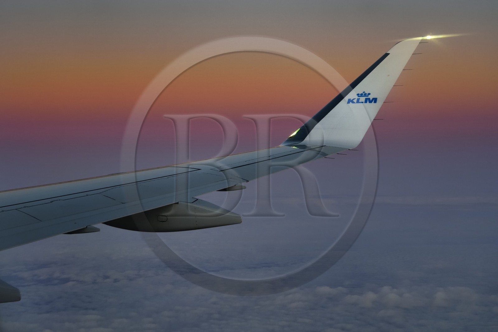 Norvège, aile d'un avion KLM en vol au dessus des nuages au coucher de soleil