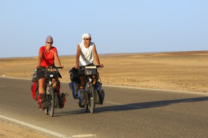 Egypt, Libyan desert, couple of cycling tourists on the road from Cairo to Bahareyya