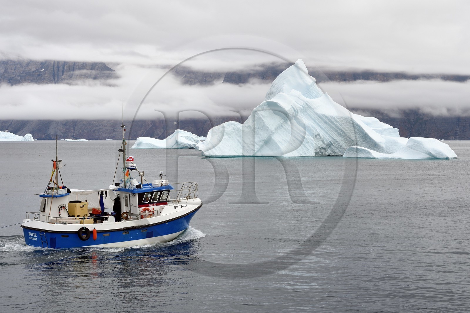 Groenland, cote ouest, Uummannaq, bateau de pêche sortant du port et icebergs en arrière plan