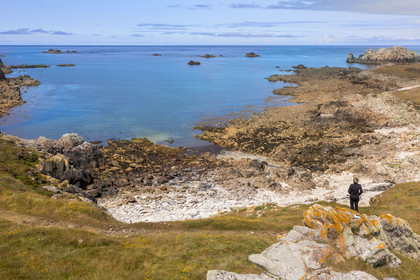 France, Finistère, Iroise Sea, Ouessant Island, hiker on the coastal path of the jagged coast and the rocks of the north coast (aerial view)