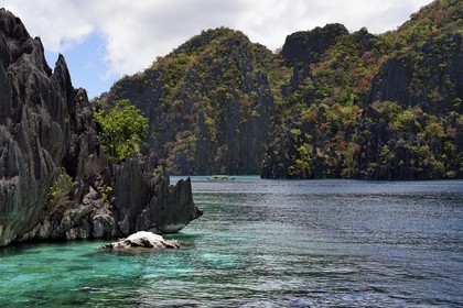 Philippines, Calamian Islands dans le nord de Palawan, Coron Island Natural Biotic Area, pirogue à balancier dans un lagon au pied des falaises de calcaire du Permien d'origine jurassique