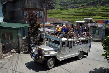 Philippines, Ifugao province, Banaue town, jeepney (elongated jeep to transport passengers) in the main street, passengers on the roof